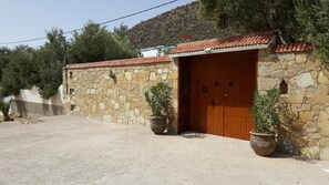 Un bâtiment en pierre avec une porte en bois et deux plantes en pot.