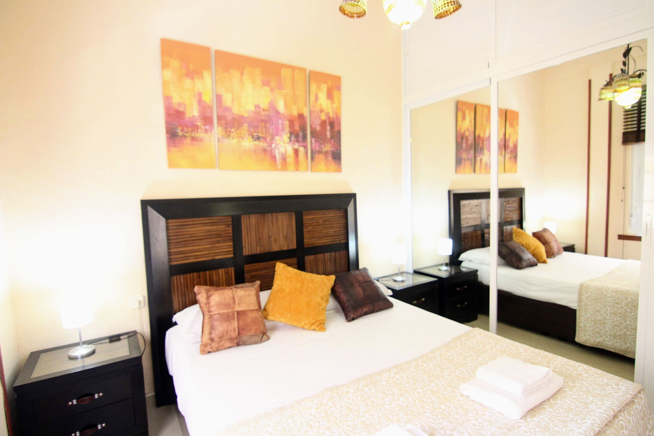 Habitación de hotel con una cama grande, una mesita de noche, un espejo y obras de arte en la pared.