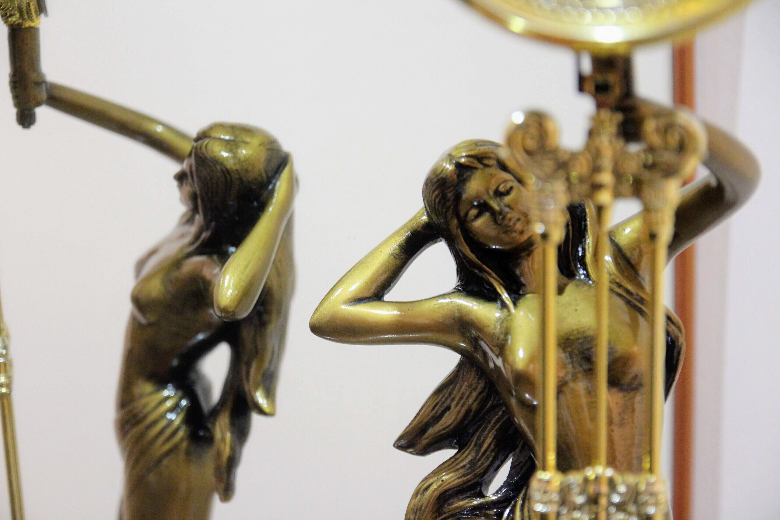 En bronzeskulptur af en kvinde med en spejlenende overflade, placeret på et stativ.