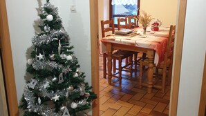 A cozy dining area with a wooden table and chairs, a small Christmas tree, and a window with a view. - Apartment/ flat - LA BRESSE (La Bresse)