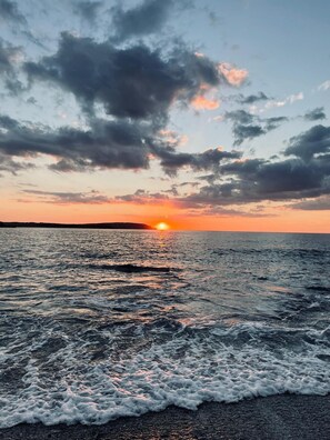 A sunset over a body of water with waves gently lapping onto the shore. - Kohinoor Trevone Holidays, Kohinoor Trevone Holidays (Trevone, Padstow)