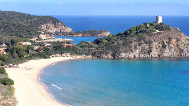 Un paysage côtier comprenant une plage, une tour située sur une colline et un petit village.