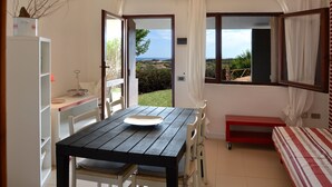 Une pièce avec une table en bois, des chaises, un lit et une vue sur l’extérieur.