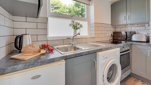 A compact kitchen with a built-in washing machine, a coffee maker, and a toaster.