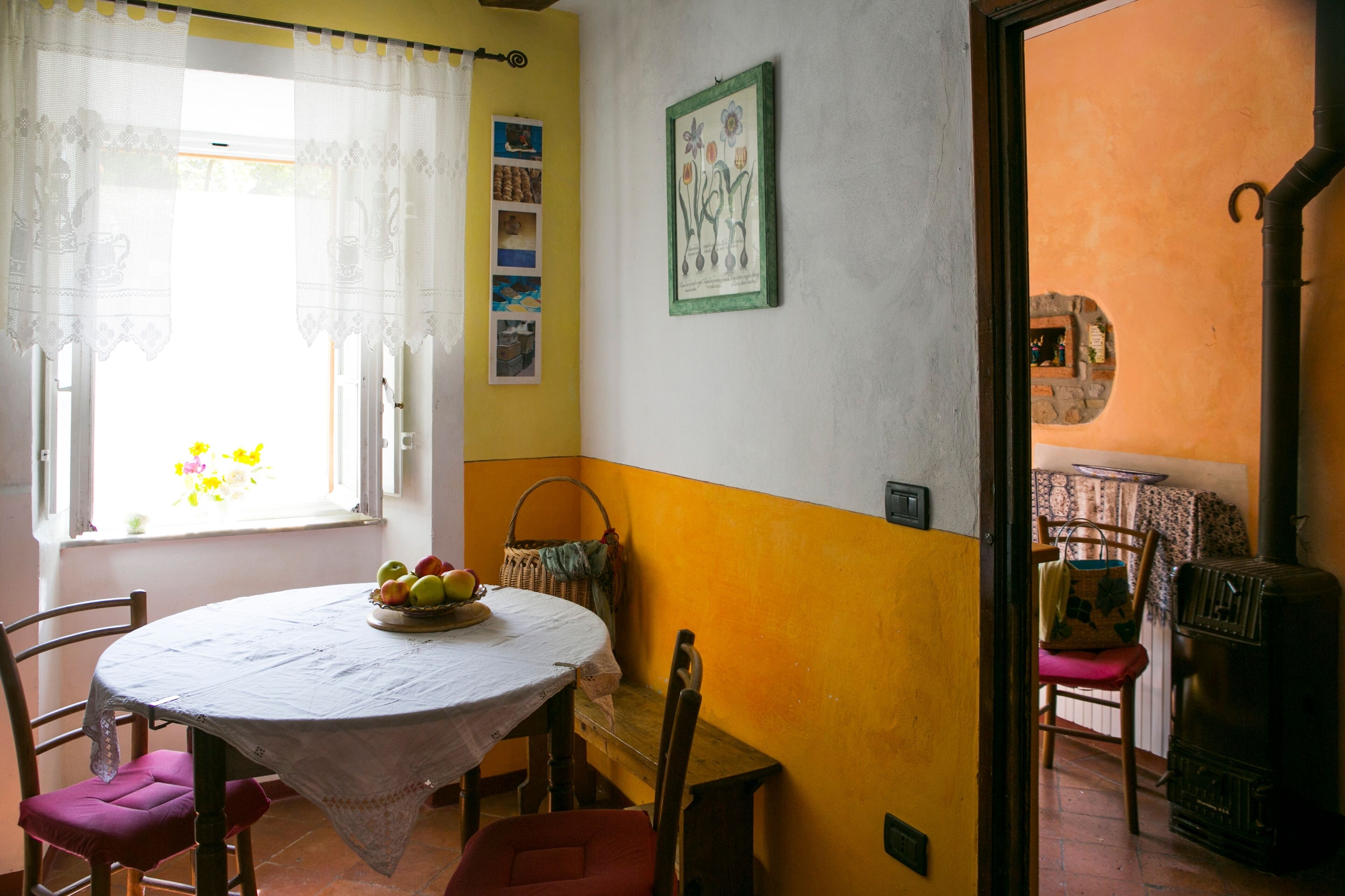 Un área de comedor con una mesa redonda, sillas y una cesta de fruta.