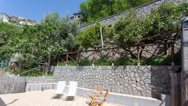 Eine Terrasse mit Steinmauern und einem Metall-Rankenwerk.