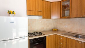 Eine kleine Küche mit Holzausstattung, einem weißen Kühlschrank, einem Gasherd und einem Geschirrspüler.