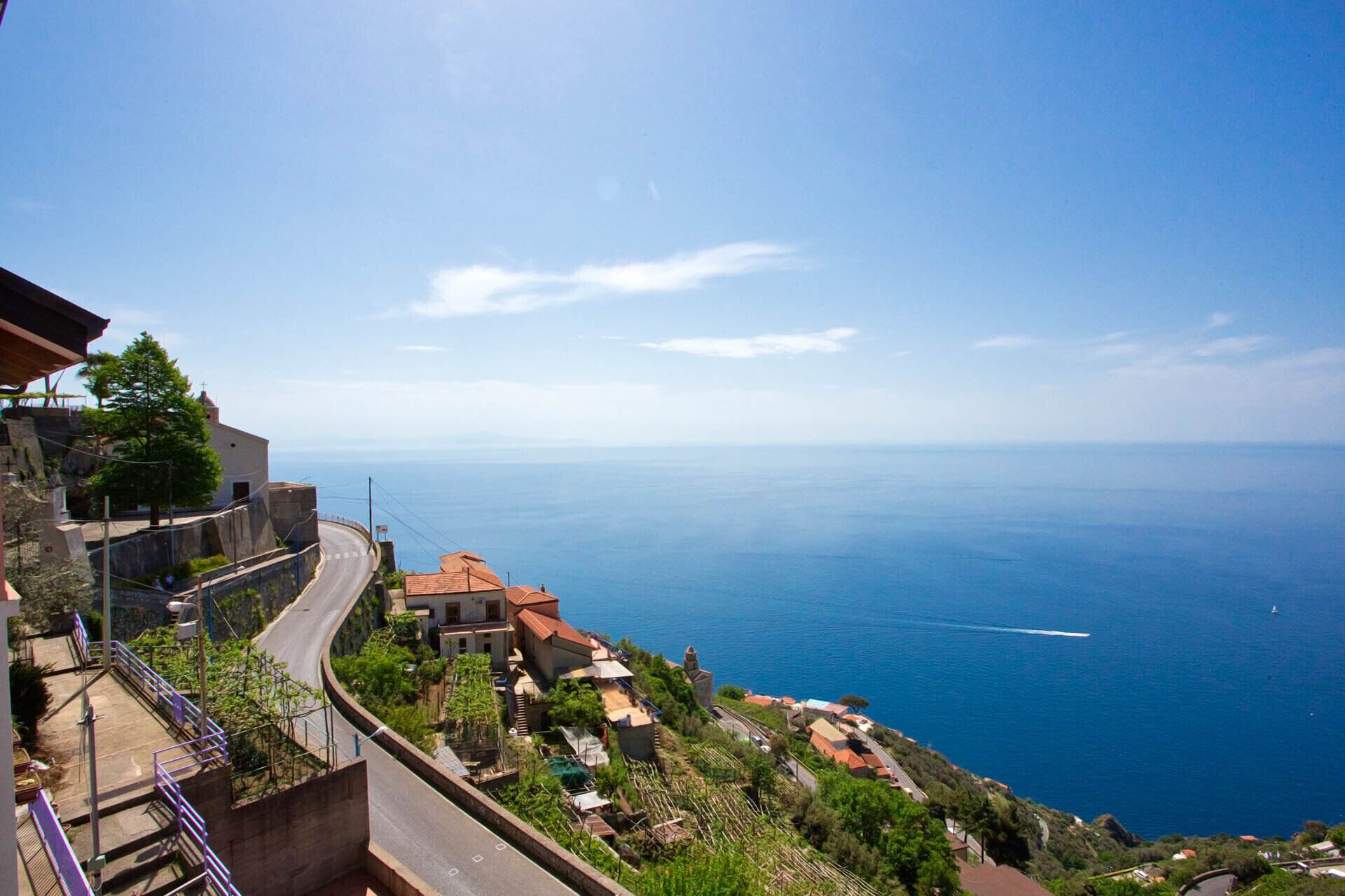 A coastal village with terraced houses, a winding road, and a view of the sea.
