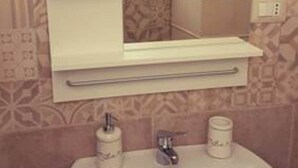 Un baño con un lavamanos blanco, un espejo y un perchero para toallas.