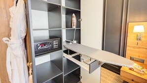 A hotel room with a built-in ironing station, a robe hanging on a door, and a bedside table with a lamp. - Aurum Hotel (Bishkek)
