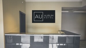A reception desk with a logo for AURUM HOTEL. - Aurum Hotel (Bishkek)