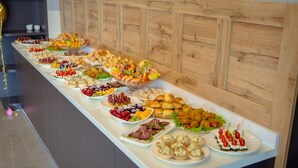 A buffet table with various food items and a cake with candles. - Aurum Hotel (Bishkek)