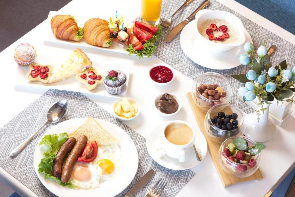 A breakfast buffet with croissants, pastries, fruits, and beverages.