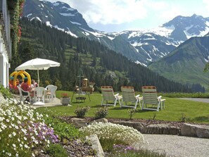 Une terrasse avec des sièges extérieurs, une balançoire et une vue sur des montagnes enneigées.