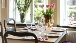 A dining area with a chandelier, a table set for four, and a window with a view of greenery.