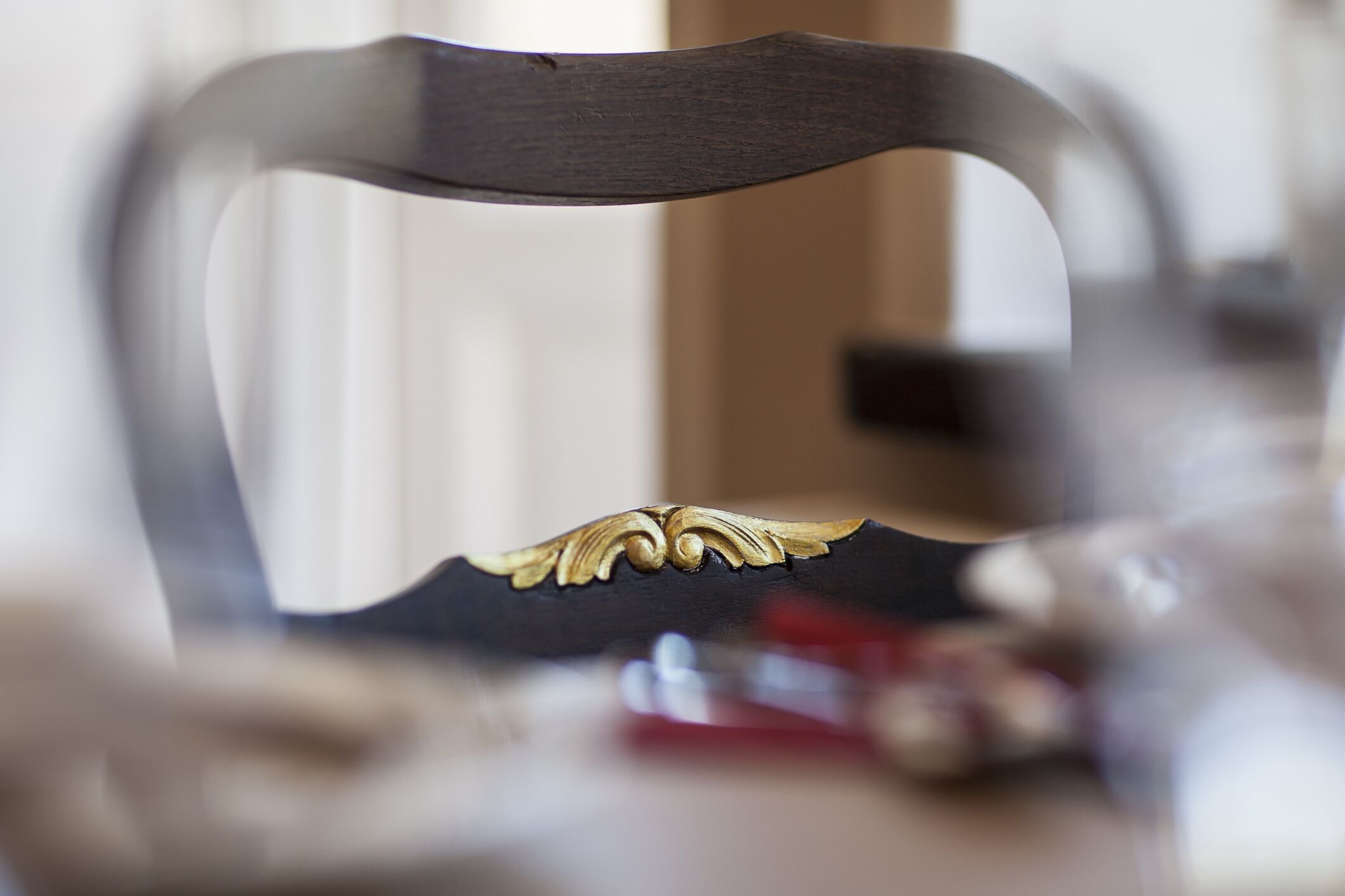 A close-up of a chair with a curved backrest and a decorative gold accent.
