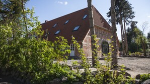 A traditional building with a sloped roof, stone walls, and a small porch area.
