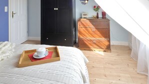 A bedroom with a bed, a wardrobe, a dresser, and a window with curtains.
