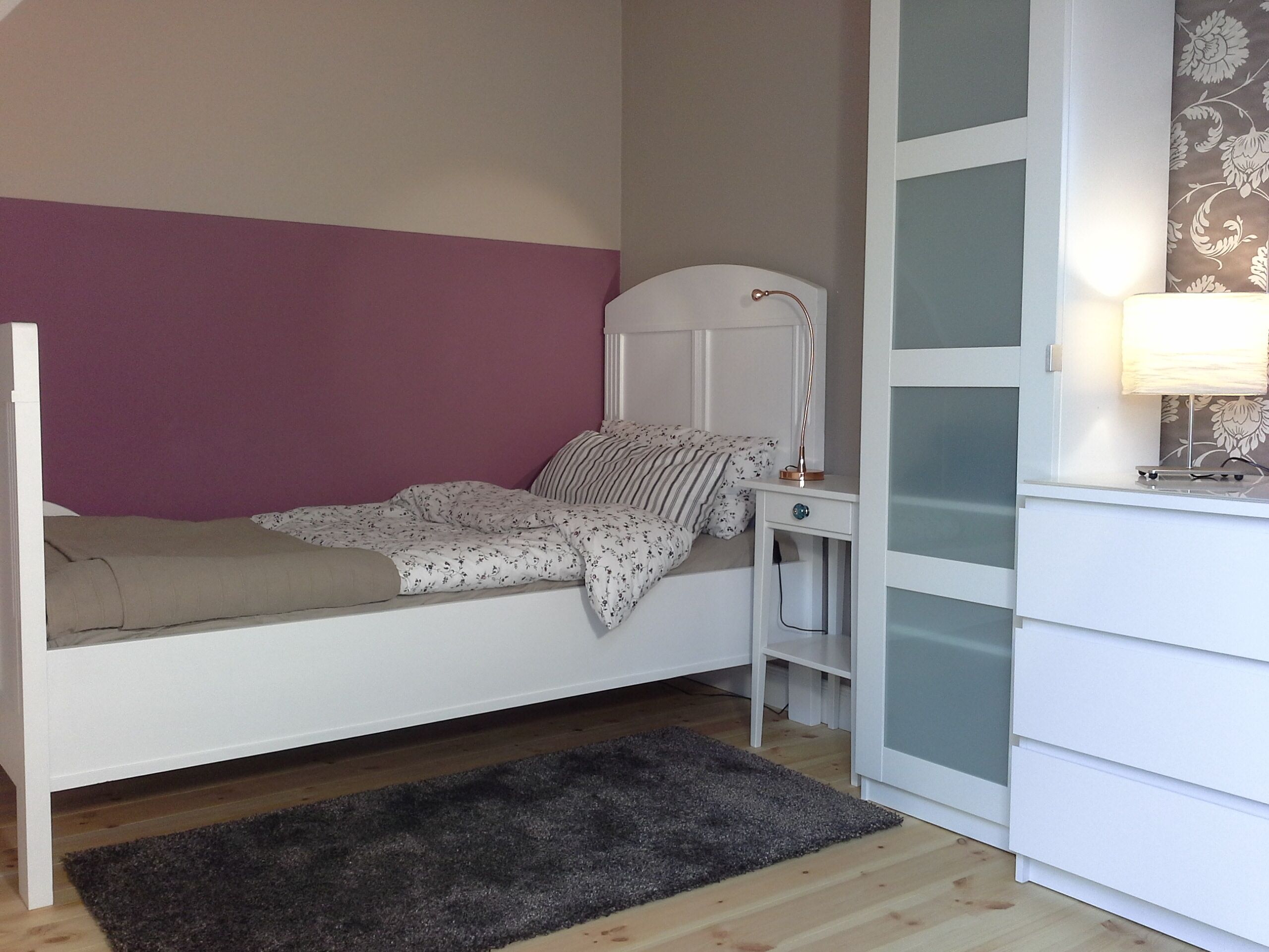 Un dormitorio con cama, mesita de noche, lámpara y cómoda.