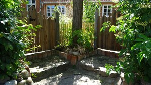 A garden area with a wooden fence, a tree, and a stone pathway.