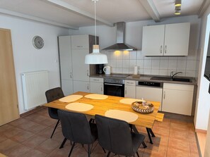Una cocina moderna con armarios blancos, una mesa de comedor de madera y sillas negras.