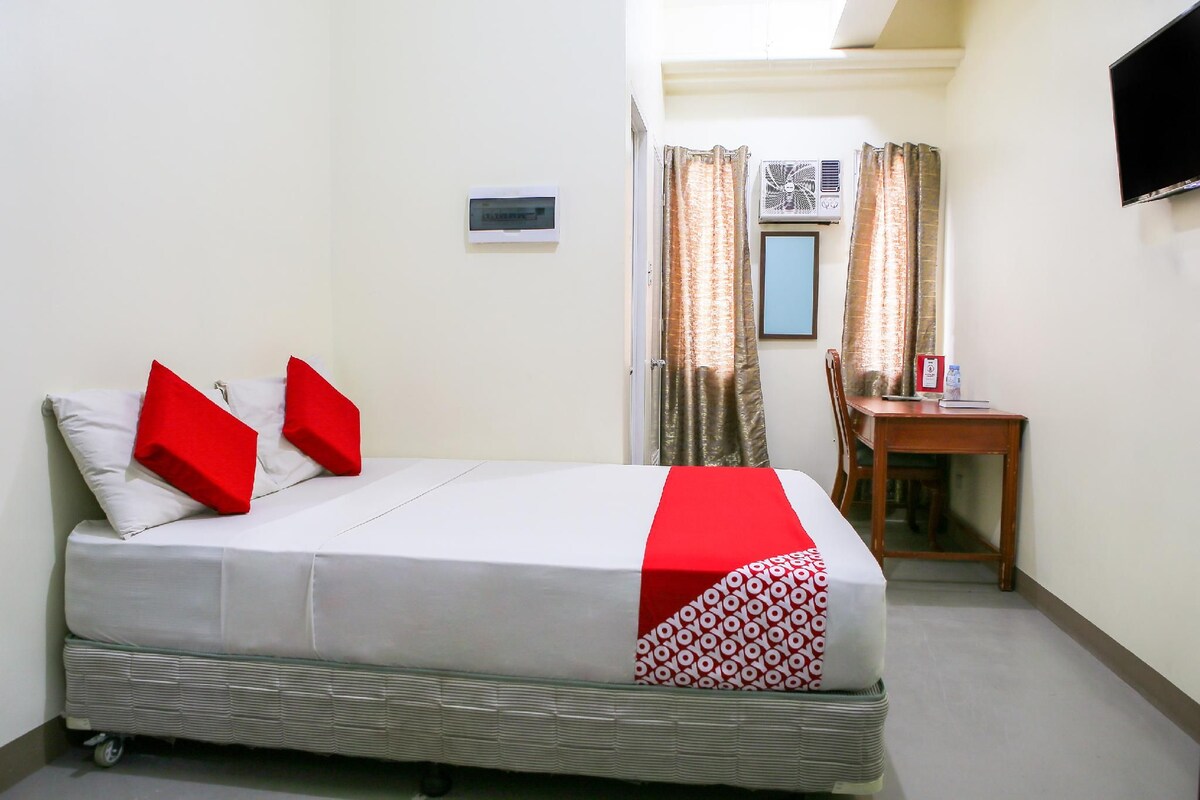 A hotel room with a bed, a desk, and a television.