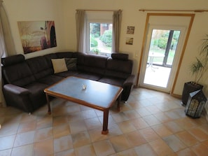 A living room with a sectional sofa, a coffee table, and a potted plant.
