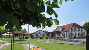 A park with a playground, a building with a red roof, and a wooden fence. - Vacation home Gala in the vacation village Altes Land - Holiday home 303 Gala 80sqm for max. 6 persons (Hollern-Twielenfleth)
