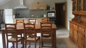 Una cocina con mesa, sillas, microondas y armarios de madera.