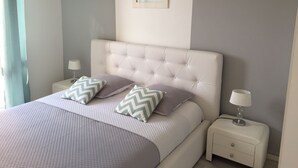 A neatly arranged bedroom with a tufted headboard, two bedside tables with lamps, and a bed with patterned bedding.