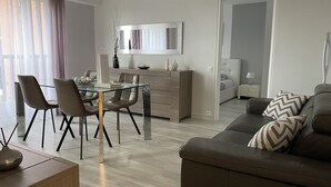 A modern living room with a glass dining table, leather sofa, and a minimalist design.