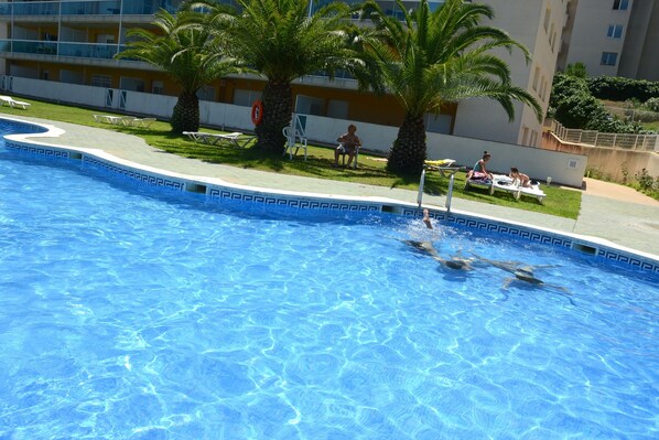 A swimming pool with clear blue water, surrounded by lounge chairs and palm trees. - OFFER PENTHOUSE GRAND Solarium PRIVATE, CONDITIONED, POOL, VERY QUIET, WIFI (Salou)