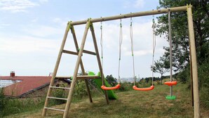 Een houten schommel met een ladder en een glijbaan in een grasveld.