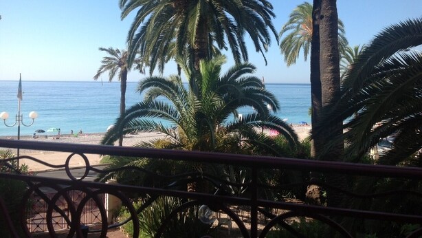 A beach view with palm trees and a clear sky. - La Terrasse du Soleil:Fantastic 3-bd apt with sundeck facing the beach! (Menton)