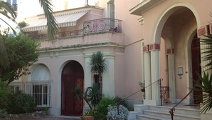 A building with a central entrance, a staircase, and a small garden area with plants. - La Terrasse du Soleil:Fantastic 3-bd apt with sundeck facing the beach! (Menton)