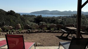 A terrace with two chairs and a table, overlooking a scenic landscape with mountains and a body of water.