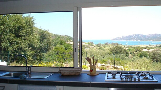 A kitchen with a large window overlooking a coastal landscape.