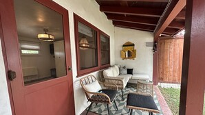 Une terrasse couverte avec des meubles en osier, un canapé blanc et un tapis à motifs.