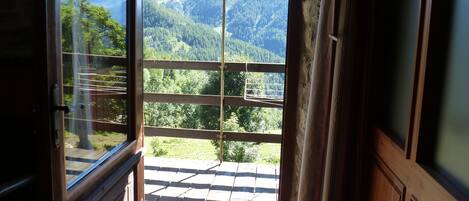 An open door leading to a balcony with a view of a mountainous landscape.