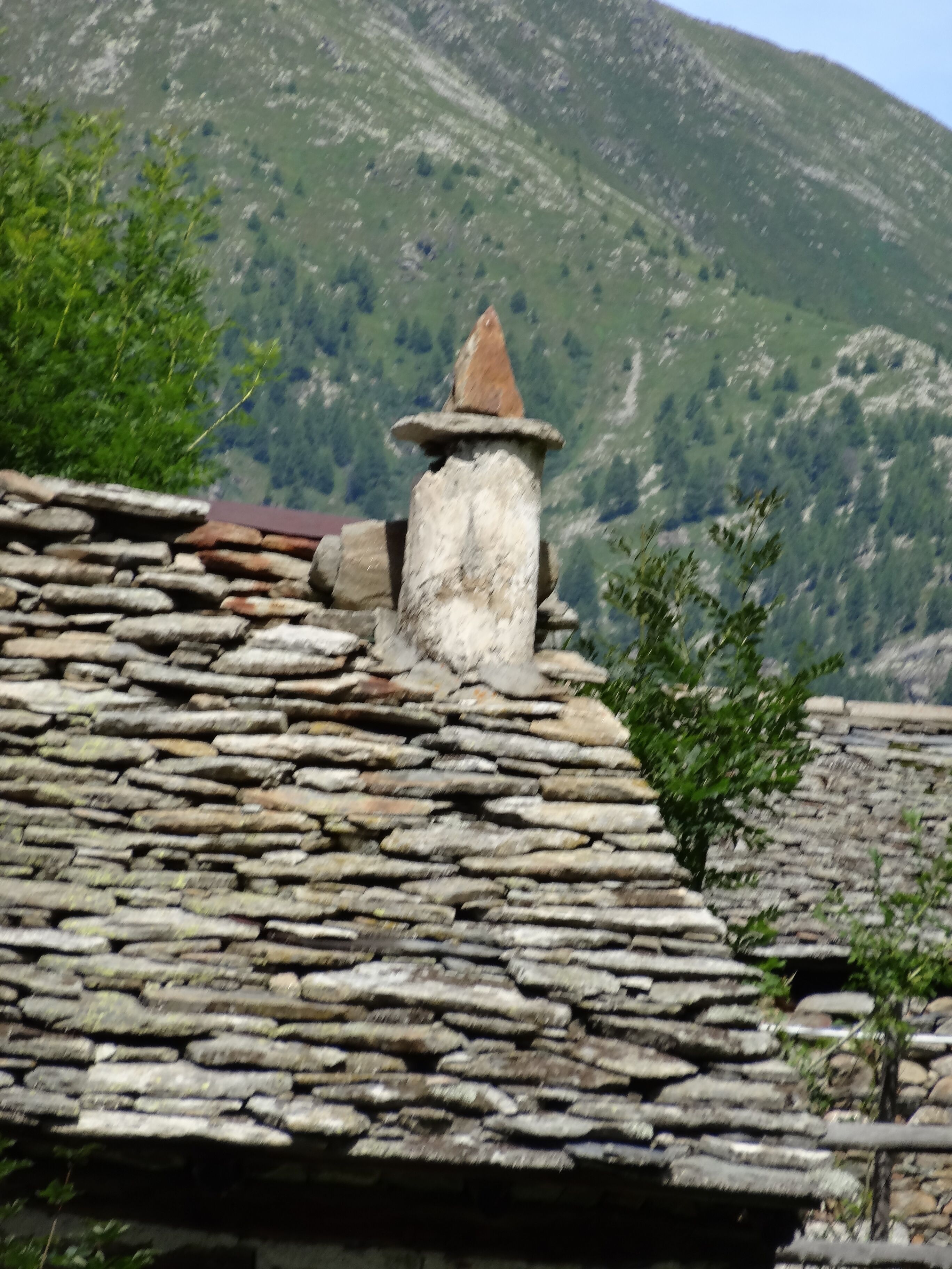 Telhado de pedra com chaminé e parede de pedra.