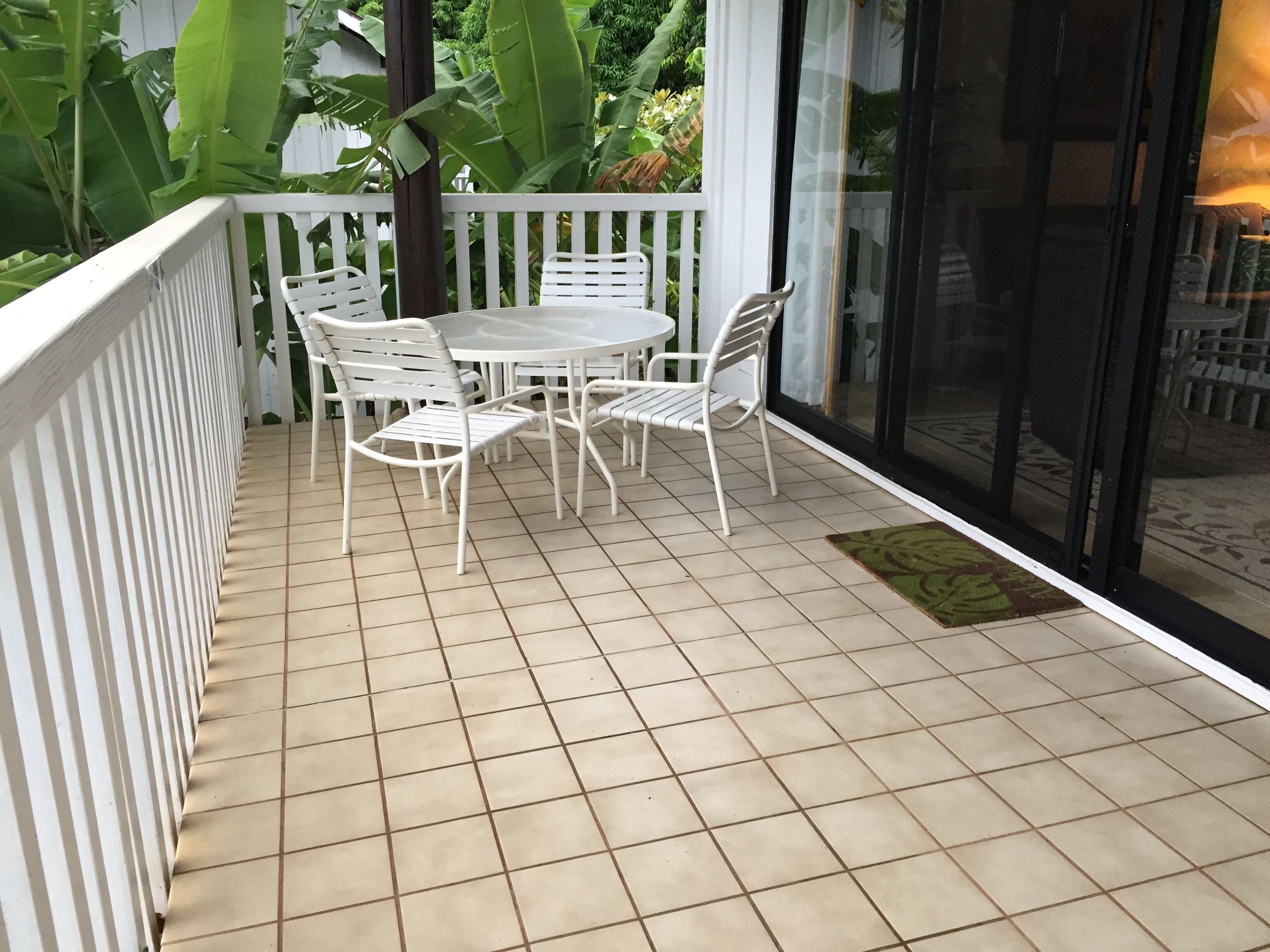 Ein Balkon mit weißer Brüstung, Fliesenboden und einem Tisch mit vier Stühlen.