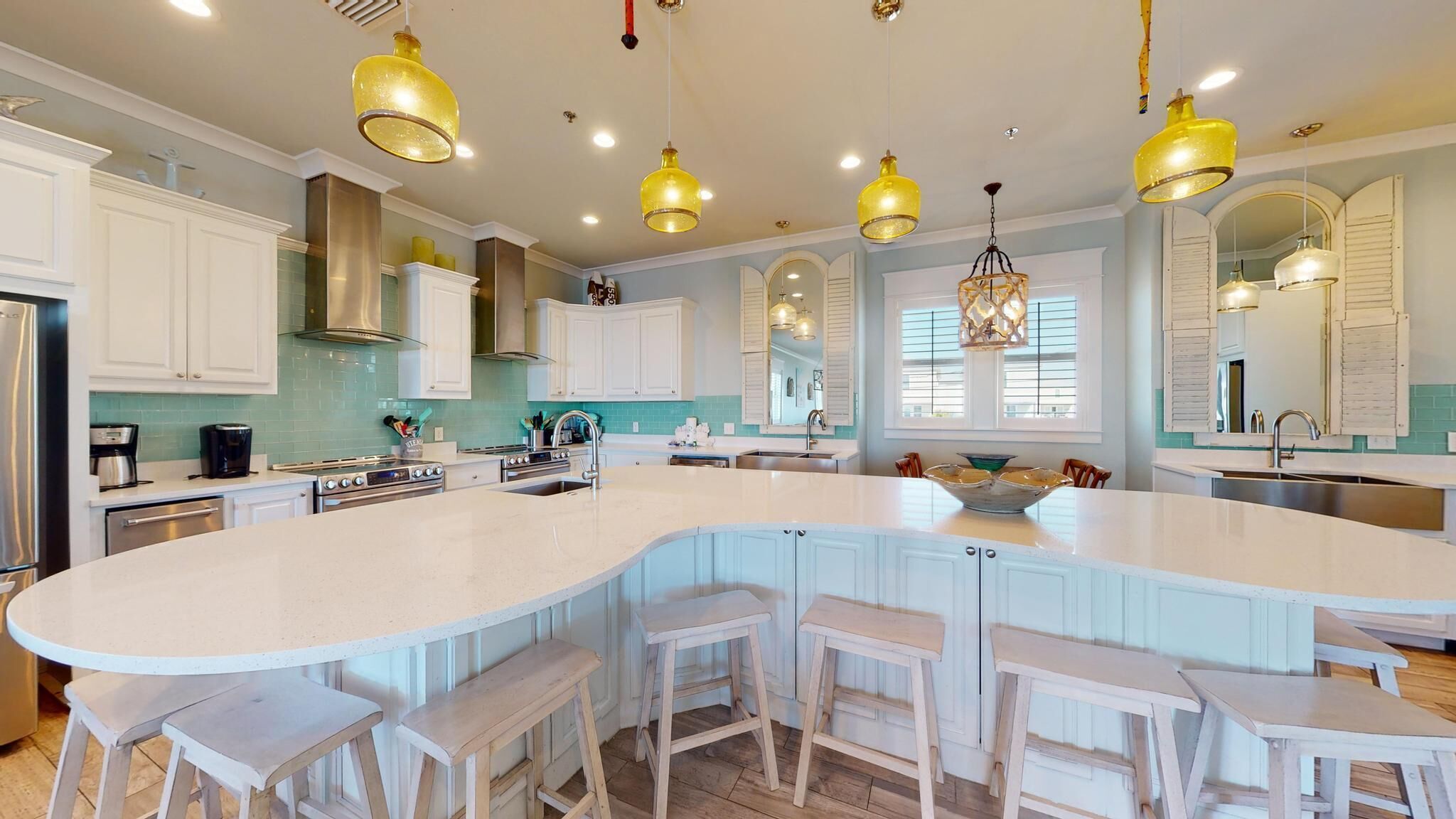 A spacious kitchen with a large island, white cabinetry, and multiple pendant lights.