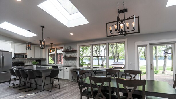 Una cocina moderna con una isla grande, taburetes de bar y un área de comedor con mesa y sillas.