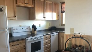 Une cuisine avec des meubles de rangement en bois, une cuisinière blanche et un lave-vaisselle encastré.