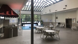 A pool area with a glass ceiling, poolside chairs, and a lifeguard stand. - Myrtle Beach Resort, Ocean View, 2 BR - 2 BA, Indoor/Outdoor Pool, B-244 (Myrtle Beach)