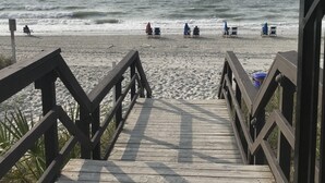 A wooden boardwalk leading to a beach with several beach chairs and umbrellas. - Myrtle Beach Resort, Ocean View, 2 BR - 2 BA, Indoor/Outdoor Pool, B-244 (Myrtle Beach)