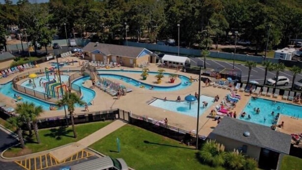 A large outdoor swimming pool area with multiple pools and a water slide, surrounded by lounge chairs and umbrellas. - Myrtle Beach Resort, Ocean View, 2 BR - 2 BA, Indoor/Outdoor Pool, B-244 (Myrtle Beach)