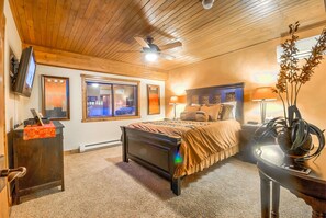 Une chambre à coucher avec un lit, une table de chevet, une lampe et un ventilateur de plafond.