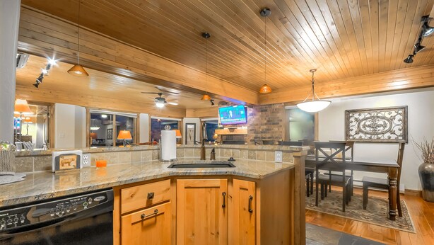 A kitchen with wooden cabinets, a dishwasher, and a stone countertop.