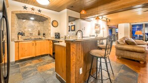 A spacious kitchen with wooden cabinets, a stone backsplash, and a bar area with stools.